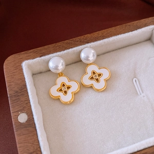 Macro detail of 18k gold plated pearl drop earrings with mother-of-pearl flower design