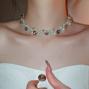 Close-up of pearl choker with heart crystals on shimmering skin of a model wearing white