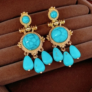 Close-up of vintage bohemian gold earrings with turquoise water drop pendants on velvet