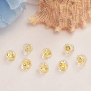 Fermoirs d'oreilles en silicone plaqué or 18K sur tissu blanc avec accents floraux