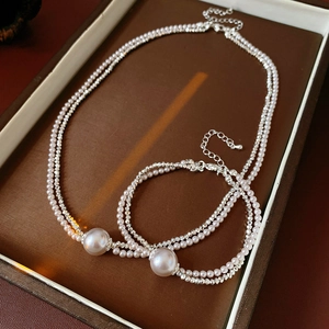 Detailed view of layered pearl necklace and bracelet set on a vintage brown display tray