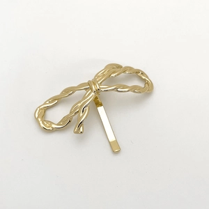 Close-up of golden bow hair clip with twisted rope texture in polished alloy metal