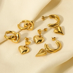 Polished 14k gold heart-shaped hoop earrings displayed on premium beige silk fabric