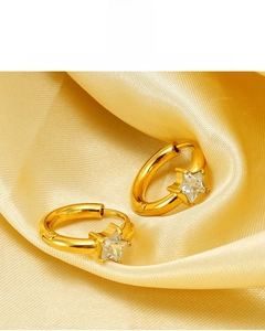 Détail de créoles étoilées plaquées or 18K avec zircon sur fond en soie jaune