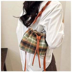 Detail of wool bucket bag with green plaid texture and brown leather drawstring strap