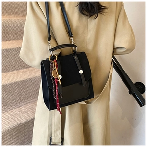 Detalle de bolso bandolera vintage negro con textura mate y colgante de raqueta de tenis