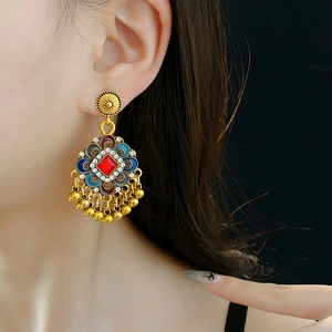 Gros plan de boucles d'oreilles vintage avec pierre rouge, émail bleu et glands dorés
