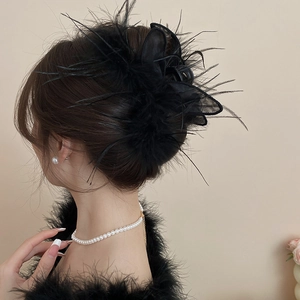 Detail of a large black feather mesh rabbit ear hair claw clip on a high bun