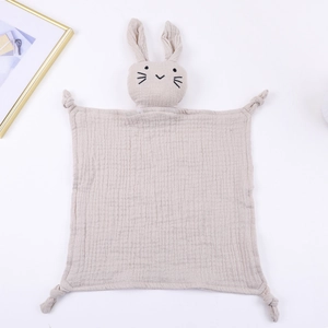 Detail of soft beige cotton gauze baby comforter with cute rabbit head and knotted corners