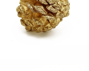 Macro shot of gold pine cone Christmas ornament with a metallic finish on white background