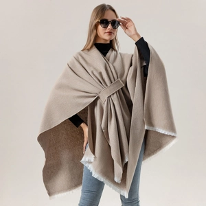 Detailed view of camel cashmere poncho with white fringes and soft textile texture