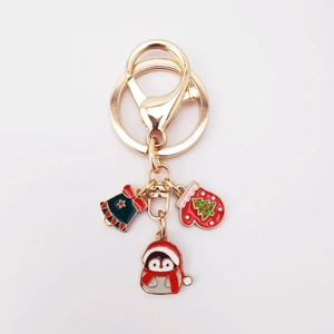 Close-up of Christmas keychain with enamel penguin, red glove, and green bell charms