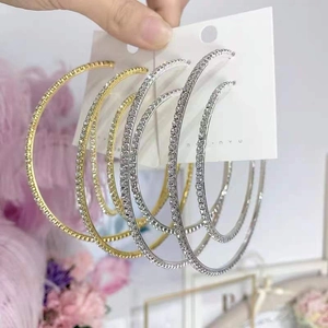 Macro detail of oversized gold and silver hoop earrings with sparkling rhinestones