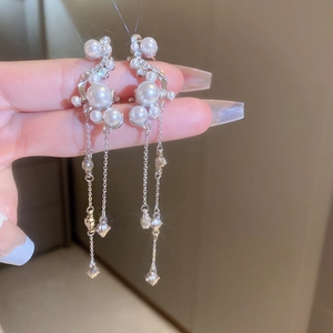 Close-up of dangling pearl tassel earrings with shimmering crystals and silver chains