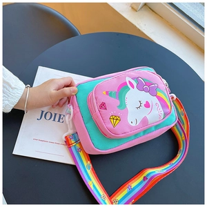 Detail of pink unicorn kids crossbody bag with rainbow strap on a black table