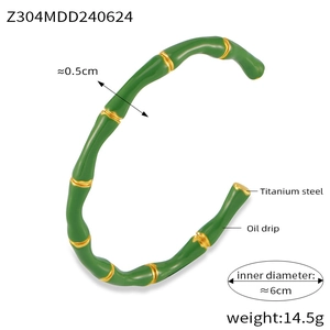 Detail view of bamboo design titanium steel bracelet with green enamel and gold accents