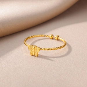 18K gold plated butterfly ring with spiral rope band on silk background