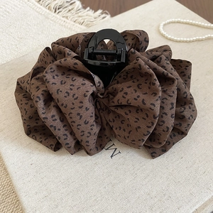 Gros plan sur une pince à cheveux en tissu léopard avec couches de mousseline et perles