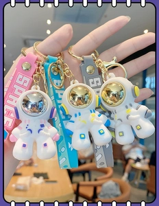Three colorful rubber astronaut keychains with SPACE lanyards held in hand