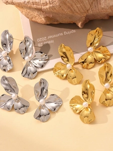 Detaillierte Makroansicht von gold- und silbernen Sonnenblumen-Ohrringen mit Perlenakzent