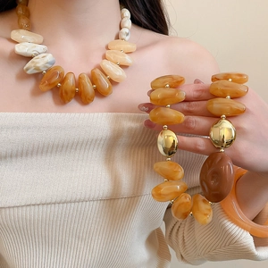 Detailed macro of amber acrylic resin necklace and bracelet set on a model with gold accents