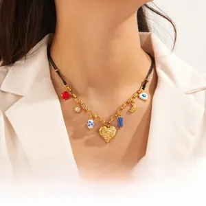 Detail of vintage heart and evil eye charms on mixed rope and gold chain necklace