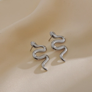 Minimalist silver snake-shaped earrings with sleek S-curve design on beige silk