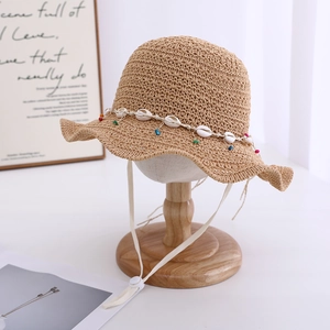 Detail of khaki straw hat featuring shell bead trim and adjustable windproof strap