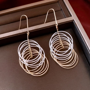 Detail of layered gold and silver circle tassel earrings with polished texture