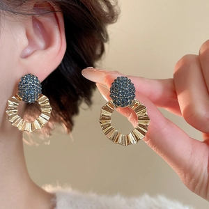 Detailed view of vintage gold textured hoop earrings with blue beaded flower embellishments