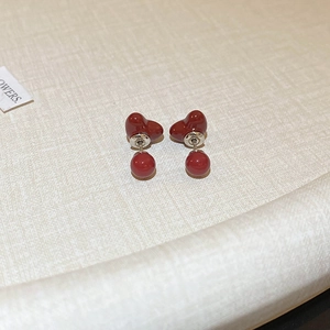 Detailansicht der tiefroten Herz-Ohrstecker auf einem strukturierten Hintergrund