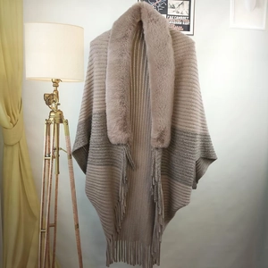 Detail of gradient knit shawl featuring a thick faux fur collar and long fringe trim