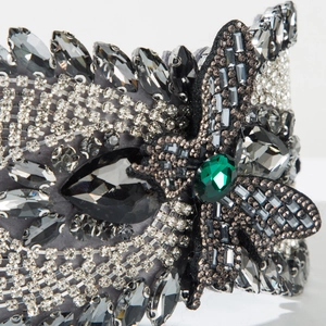 Macro detail of luxury velvet headband with green gemstone and marquise rhinestones