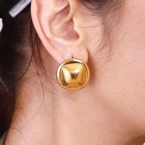 Close-up of a minimalist gold square earring with a polished mirror finish on a model