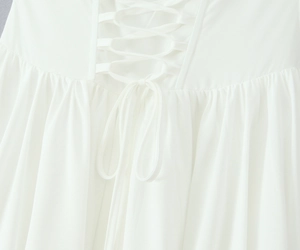 Détail du dos d'une robe blanche avec laçage croisé réglable et finitions plissées