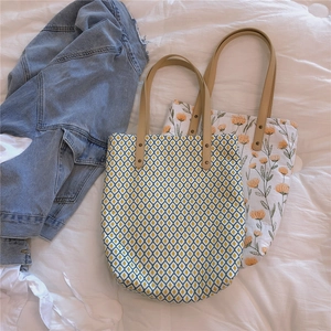 Détail de sacs cabas en toile à fleurs avec poignées en cuir renforcées