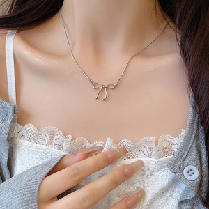 Primo piano di una collana in acciaio al titanio argento con ciondolo a fiocco minimalista