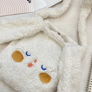 Dettaglio della borsa a tracolla in peluche bianco con ricamo viso di cane carino