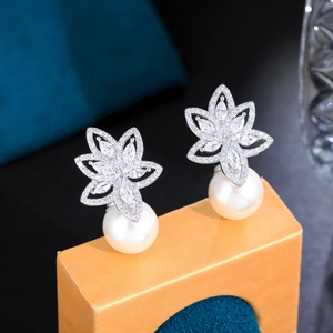 Macro detail of elegant flower-shaped pearl earrings with silver base and micro-set zircons