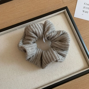 Détail d'un chouchou gris tricoté à la main avec texture tissée douce dans un coffret