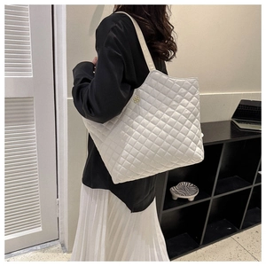 Détail du sac cabas matelassé blanc avec logo floral doré et finition brillante