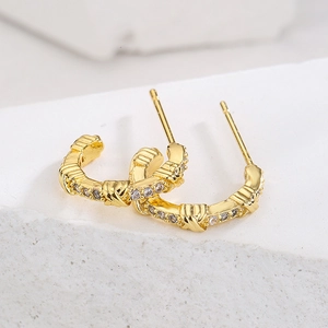 18K gold plated copper stud earrings with twisted texture and zircon stones on white stone
