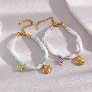 Detailed macro of 18K gold plated stainless steel seashell charm bracelets with floral fabric