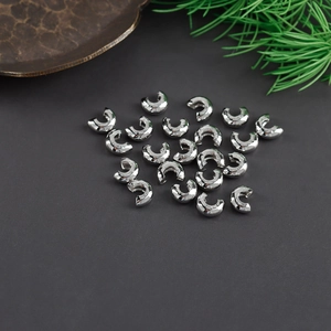 Close-up of bright silver crescent crimp bead covers for professional DIY jewelry making