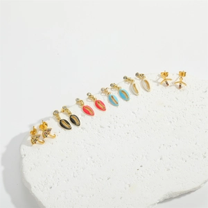 Detailed macro view of gold-plated shell and umbrella earring set on stone base