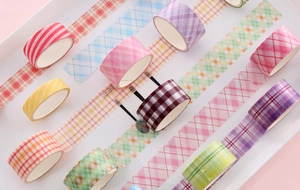 Top view of colorful checkered and striped washi tape rolls on a white tray