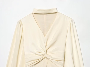 Dettaglio dell'elegante camicetta in raso beige con nodo a torsione e scollo a V setoso