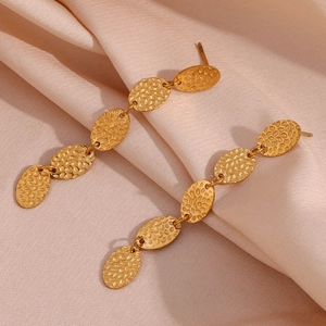 Gros plan des boucles d'oreilles pendantes dorées avec plaques ovales martelées