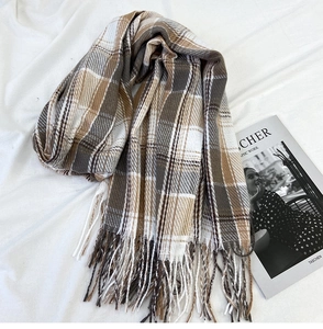 Detail view of coffee and beige plaid scarf with fringes on white fabric
