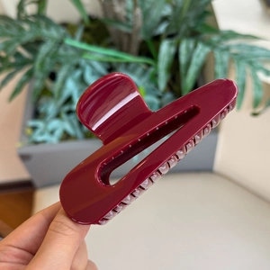 Dettaglio macro della grande pinza per capelli bordeaux lucido con finitura in resina
